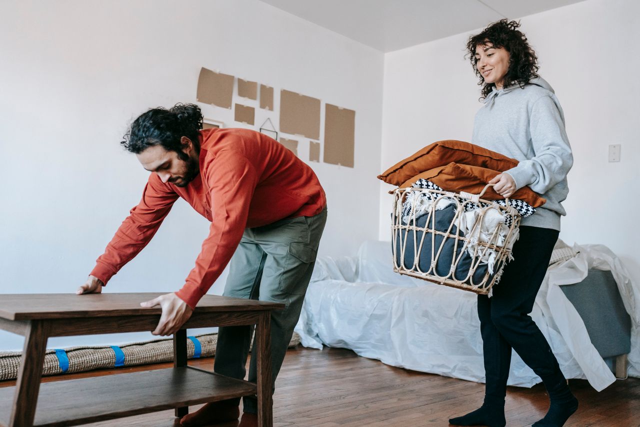 hero-02 Un couple rangeant des meubles et préparant des cartons dans un appartement moderne en vue d’un déménagement.